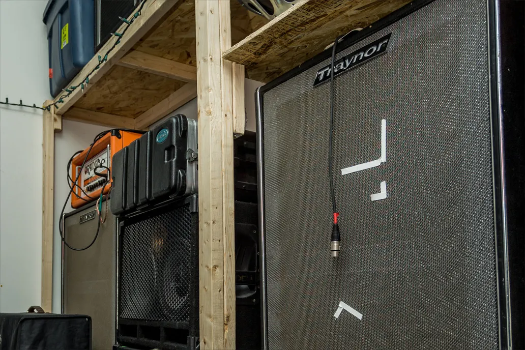 Marsonic rehearsal room amp wall with shelves, cables, and stored gear